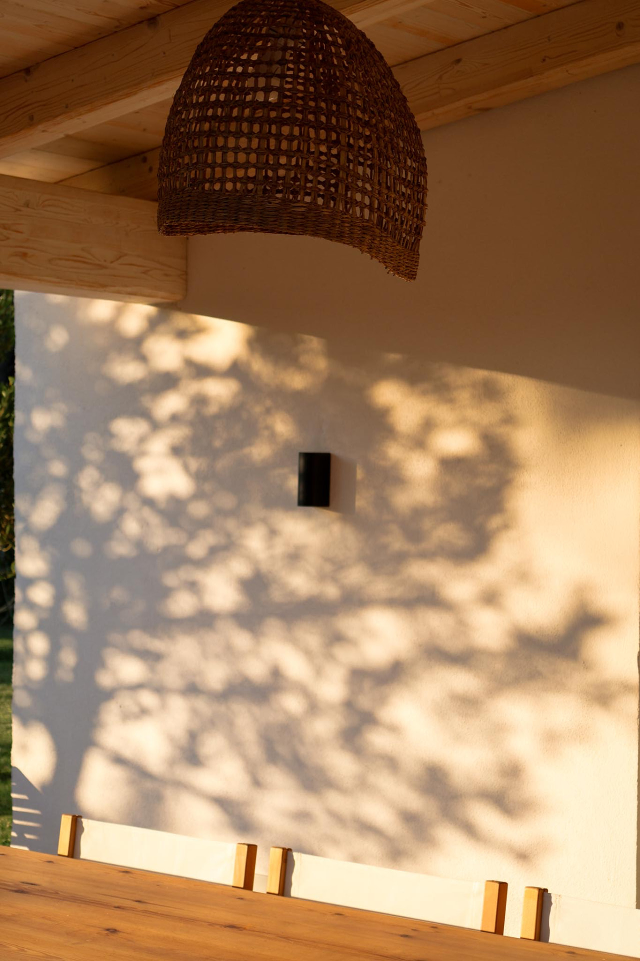 Veranda al tramonto: lampada in rattan, tavolo in legno e sedie